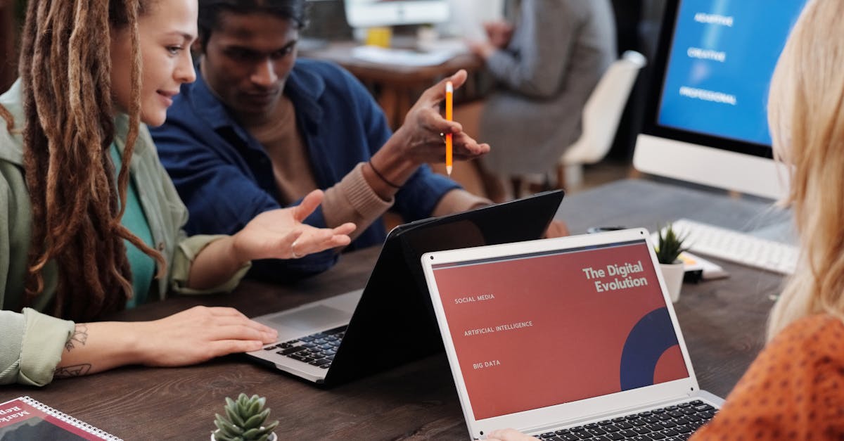Diverse team collaborating with laptops in a modern office setting, discussing digital evolution.